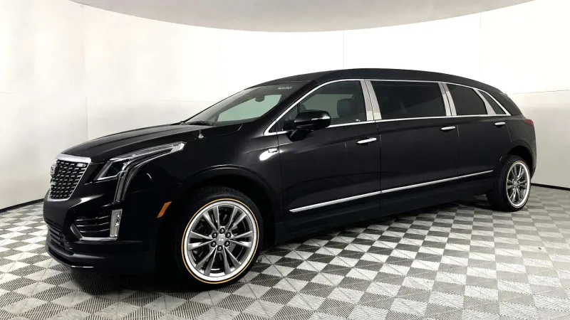 Black luxury extended limousine SUV parked on checkered floor in white-walled showroom