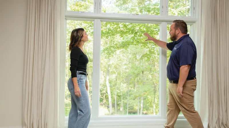 An NG Windows representative presenting an Infinity by Marvin fiberglass window sample during a no-pressure consultation.