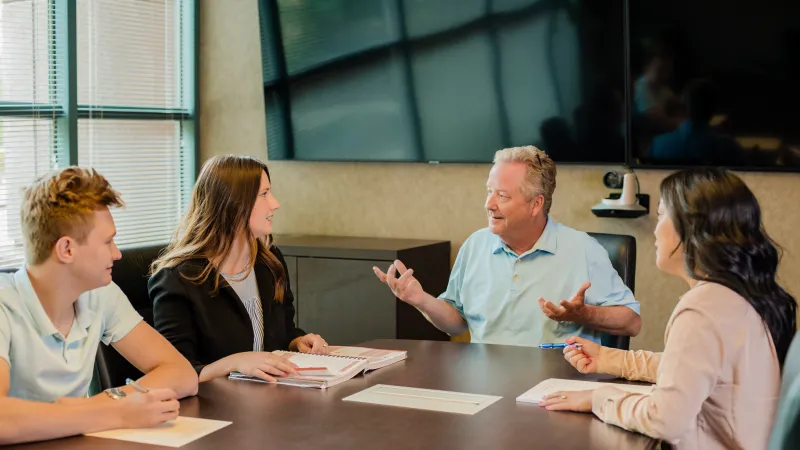 Four people engaged in a business meeting around a conference table in a modern office setting.