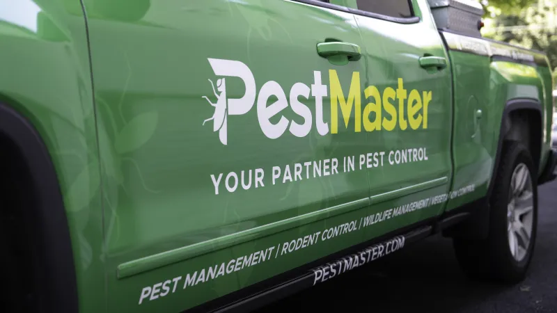 Green PestMaster Greer truck with branding and services listed, showcasing pest control and management focus.