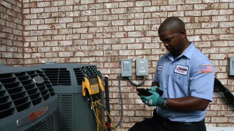HVAC technician inspecting air conditioning unit with tools in hand, wearing gloves and a blue uniform.