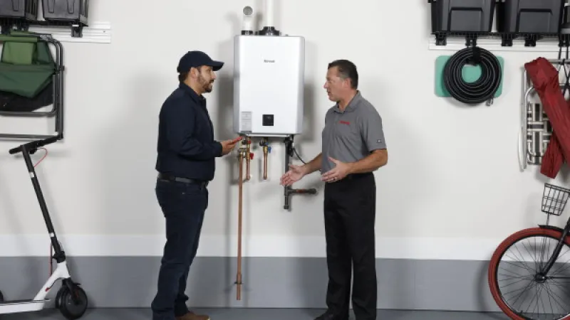 Technician explaining tankless water heater installation to homeowner in organized garage space