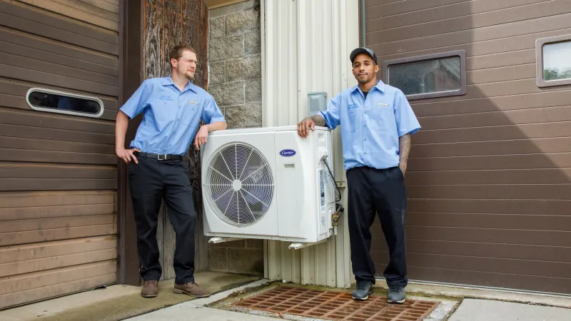 a couple of men standing outside a house with a fan