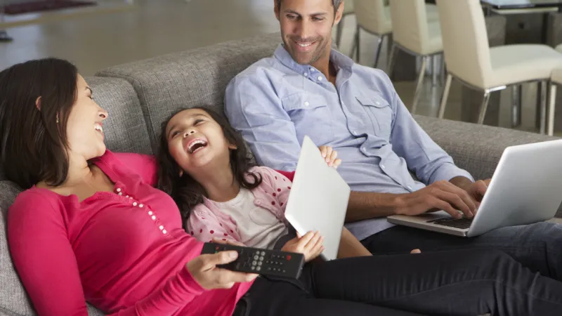 a group of people sitting on a couch with laptops