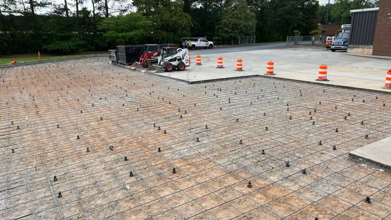 Construction site showcasing a concrete slab with rebar grid and machinery, ready for pouring concrete.
