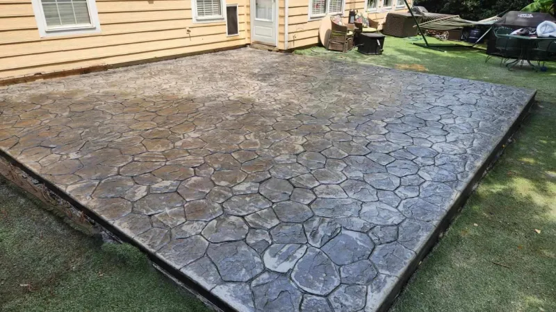 A newly stamped concrete patio with a stone pattern, enhancing the backyard's outdoor living space.