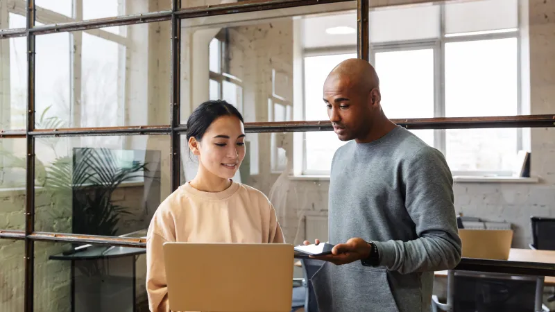 a man talking to a woman holding her laptop to show him something