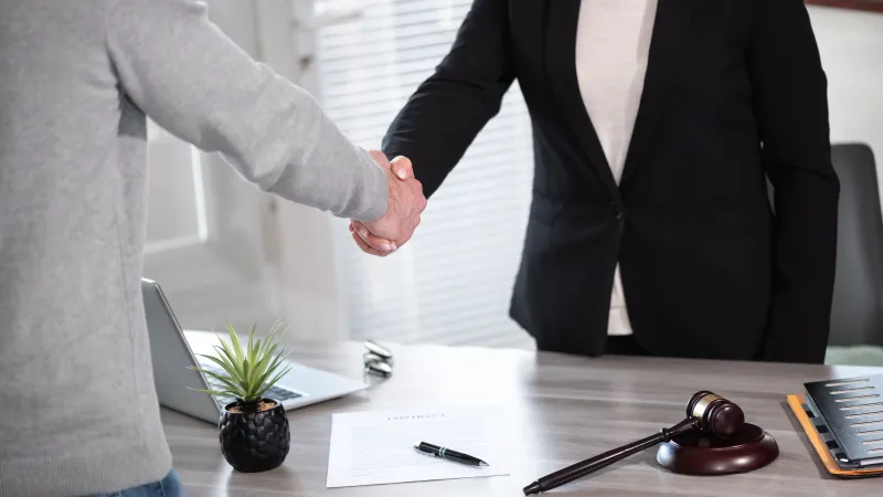 a lawyer shaking hands with her client