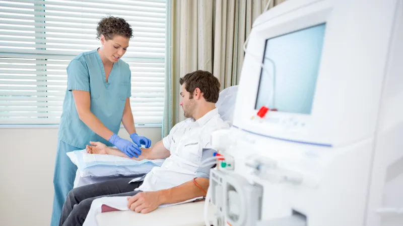 A nurse assists a patient during a dialysis treatment in a medical setting.