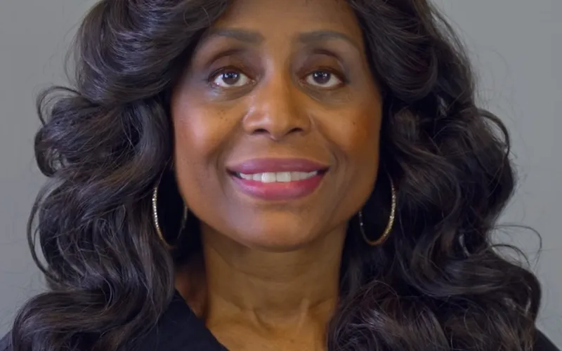 Smiling woman with long curly hair wearing Georgia Interventional Medicine jacket and hoop earrings