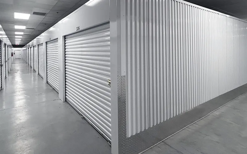White storage unit hallway with metal roll-up doors in a clean, organized facility.