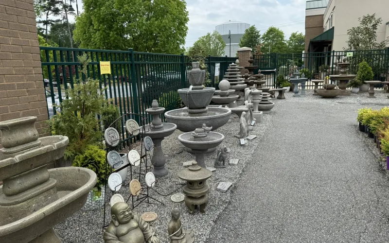 a fountain with a statue in the middle of a courtyard with trees and buildings
