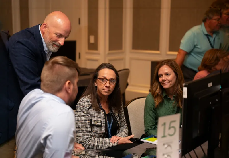 a group of people sitting at a table looking at a computer