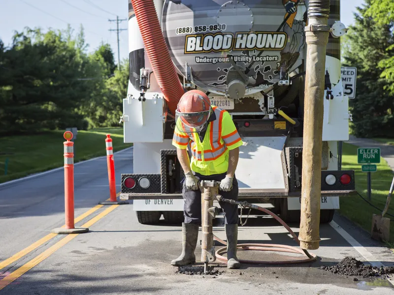 Man from Blood Hound using jackhammer to dig a hole in the road