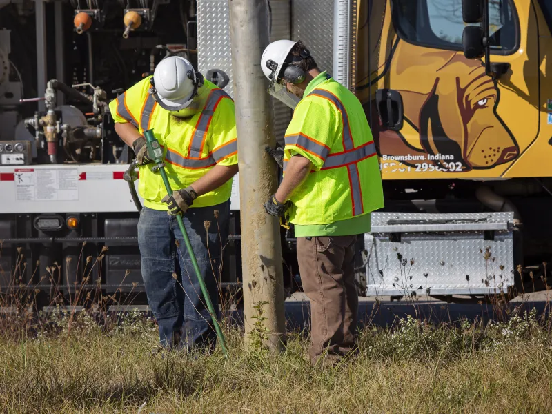 Two men from Blood Hound Underground Utility Locators performing vacuum excavation with truck
