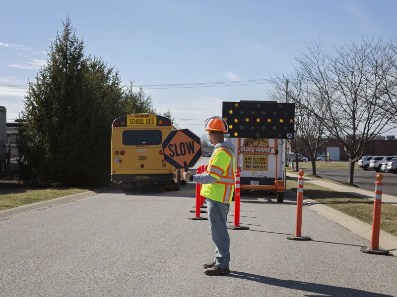 Man holding a slow sign to allow school bus traffic safely