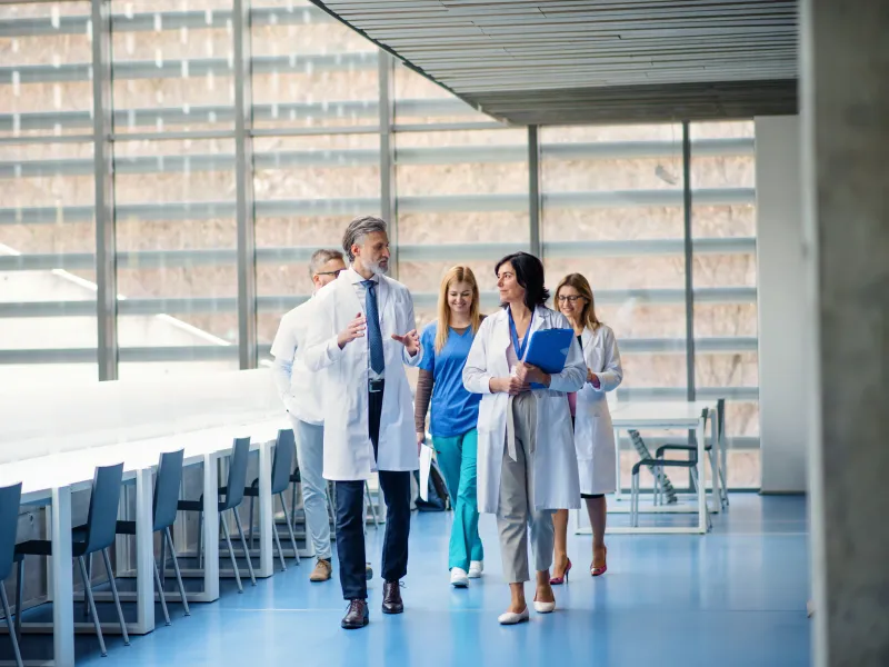 a group of people standing in a room with chairs and tables