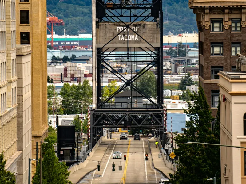 View of the Port of Tacoma vertical lift bridge amid urban buildings and traffic in Washington state.