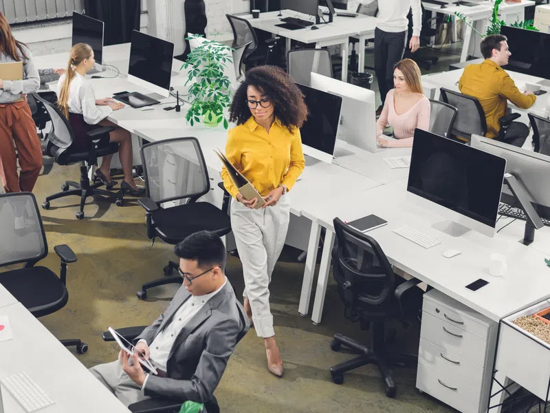 Modern open office with diverse young professionals working on computers and collaborating throughout the space
