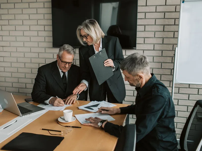Three business professionals collaborating over documents in a modern office meeting room