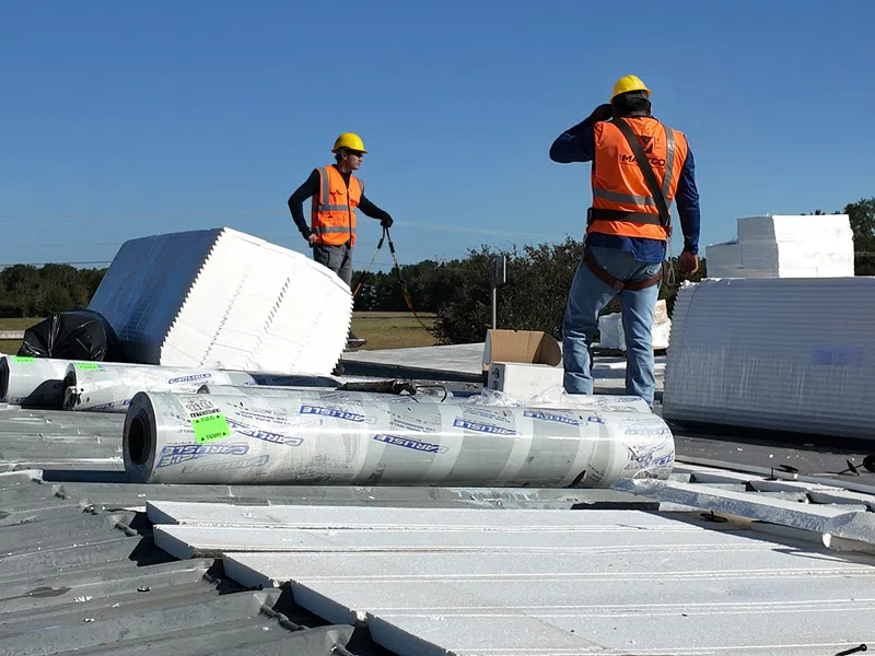 Mattco crew staging Carlisle TPO membrane and insulation over a metal roof for a commercial roof replacement