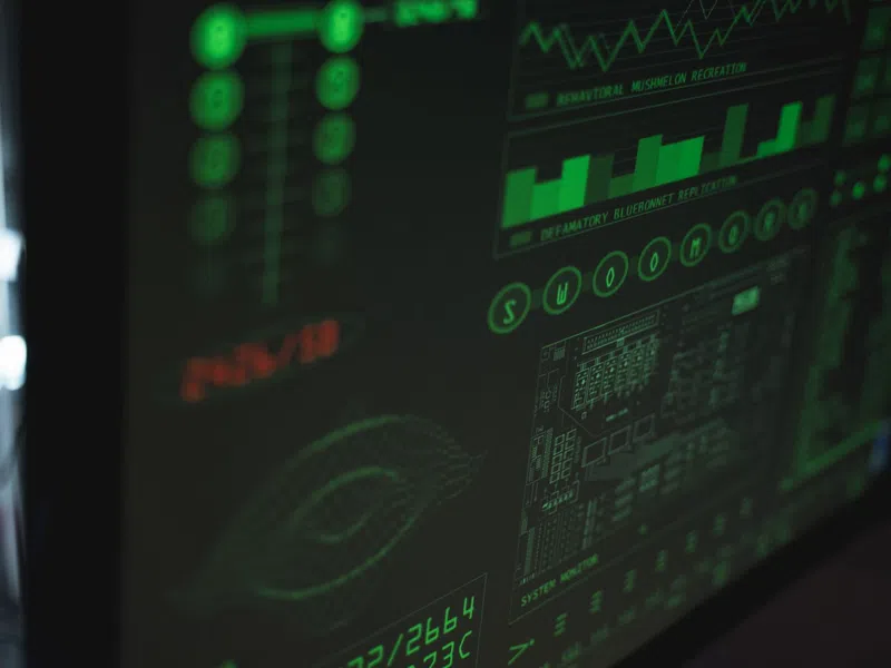 Close-up of a digital screen displaying green data graphs, charts, and system information with sci-fi style interface.