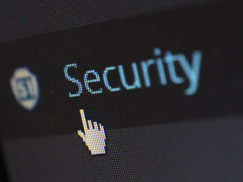 Cursor pointing at the word Security on a digital screen with a shield icon, emphasizing online protection
