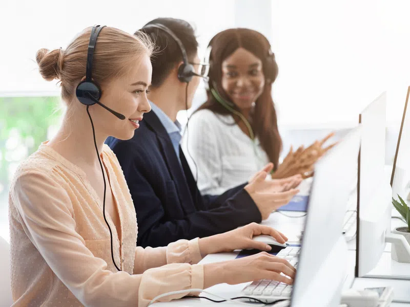 Customer support team working with headsets and computers in a bright office environment