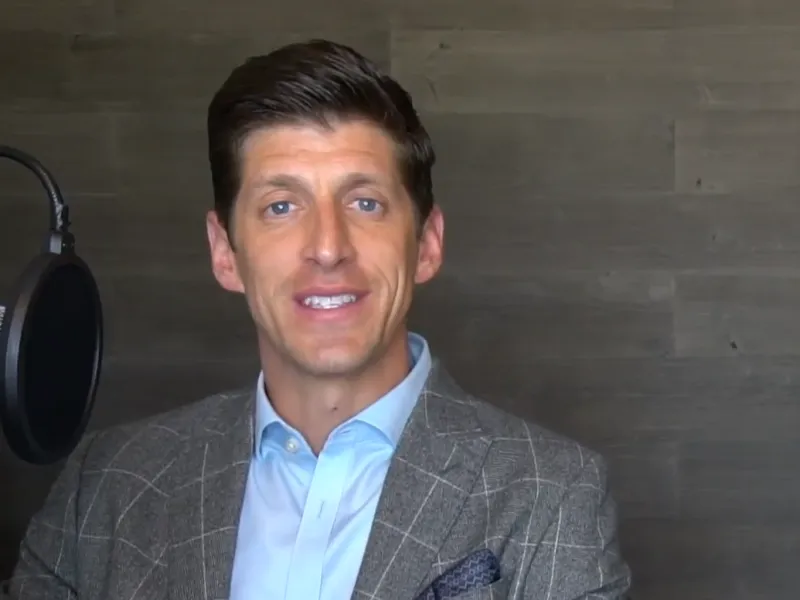a man wearing a suit and tie smiling at the camera