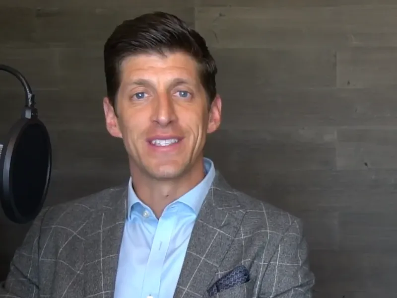 a man wearing a suit and tie smiling at the camera