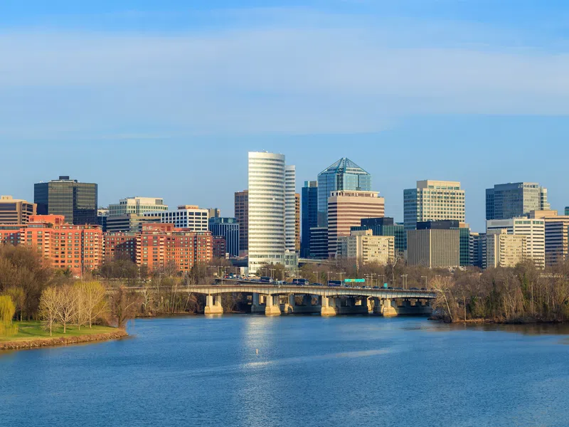 Skyline of Arlington Virginia with Potomac River and Key Bridge in clear daylight under blue sky.