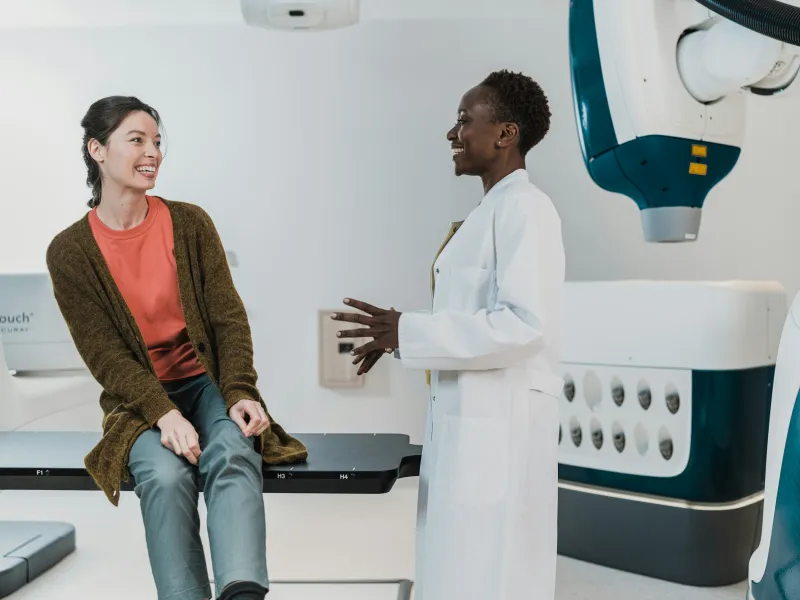 Doctor discussing treatment with patient sitting on examination table in modern medical room.