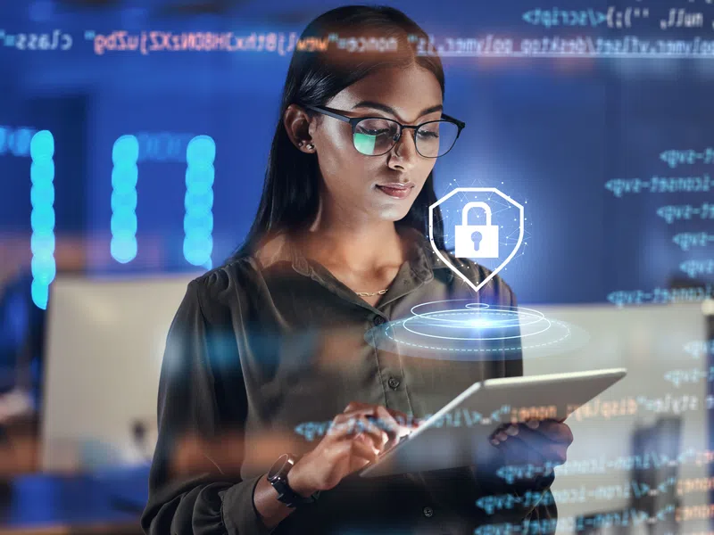 Woman using tablet with digital lock icon and coding overlays symbolizing cybersecurity and data protection.