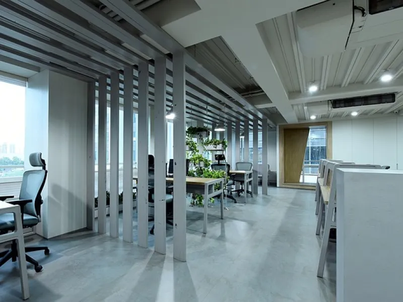 Modern office interior with ergonomic chairs, desks, and green plants under bright ceiling lights
