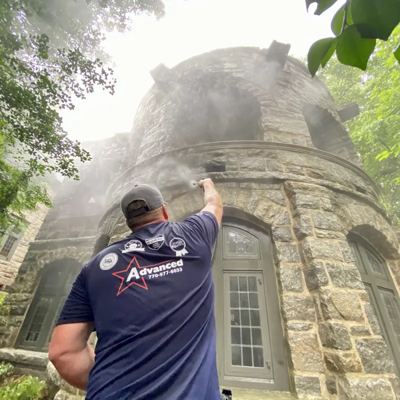 a man standing in front of a stone building with a tree and fog