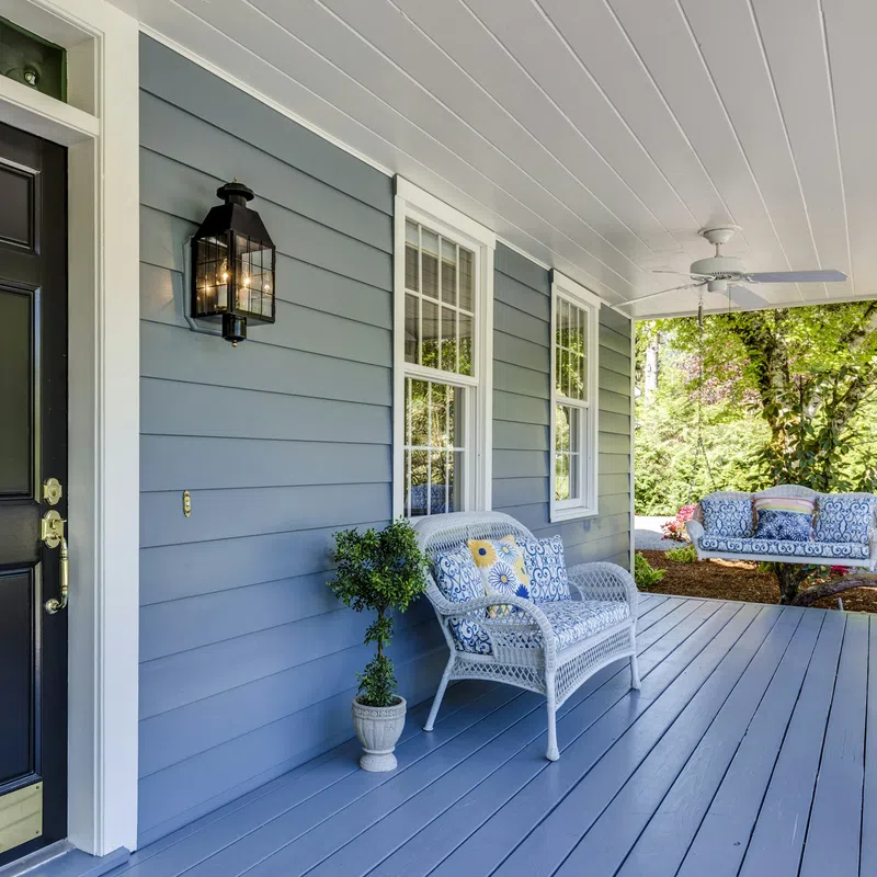 Charming porch with gray walls, stylish lantern, and comfortable seating in a serene outdoor setting.