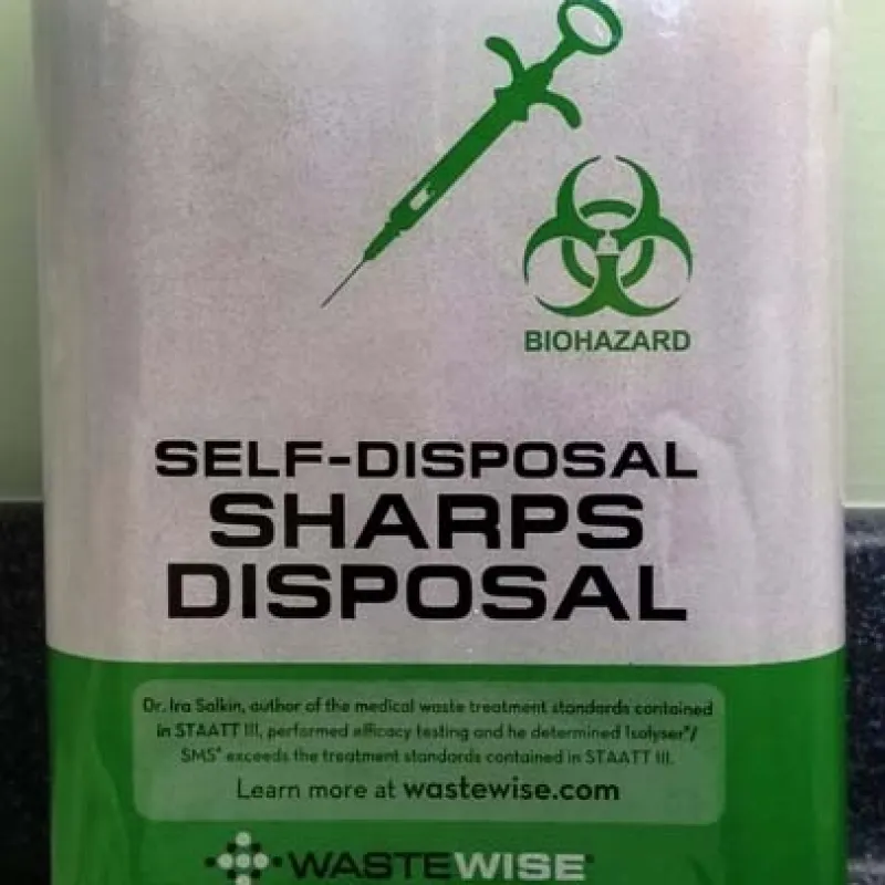 Isolyser SMS 2400 biohazard container for self-disposal of sharps with green syringe and biohazard symbol.