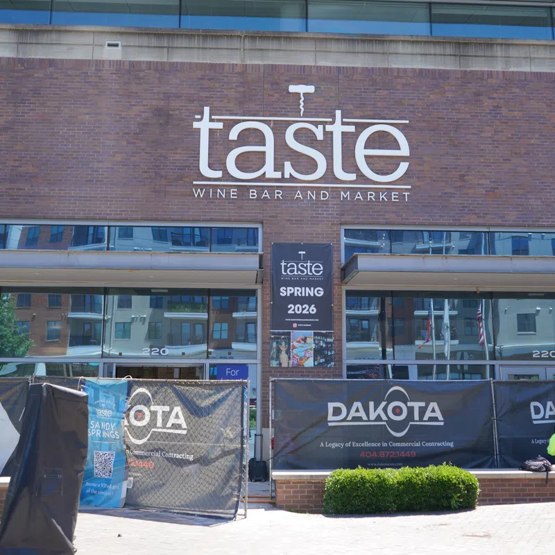 Taste Wine Bar and Market storefront with signage and construction barriers in front during daylight.