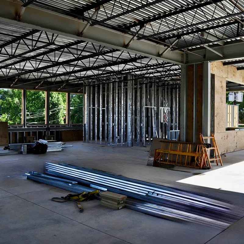 Interior of a partially constructed commercial building with metal framing and open ceiling beams.