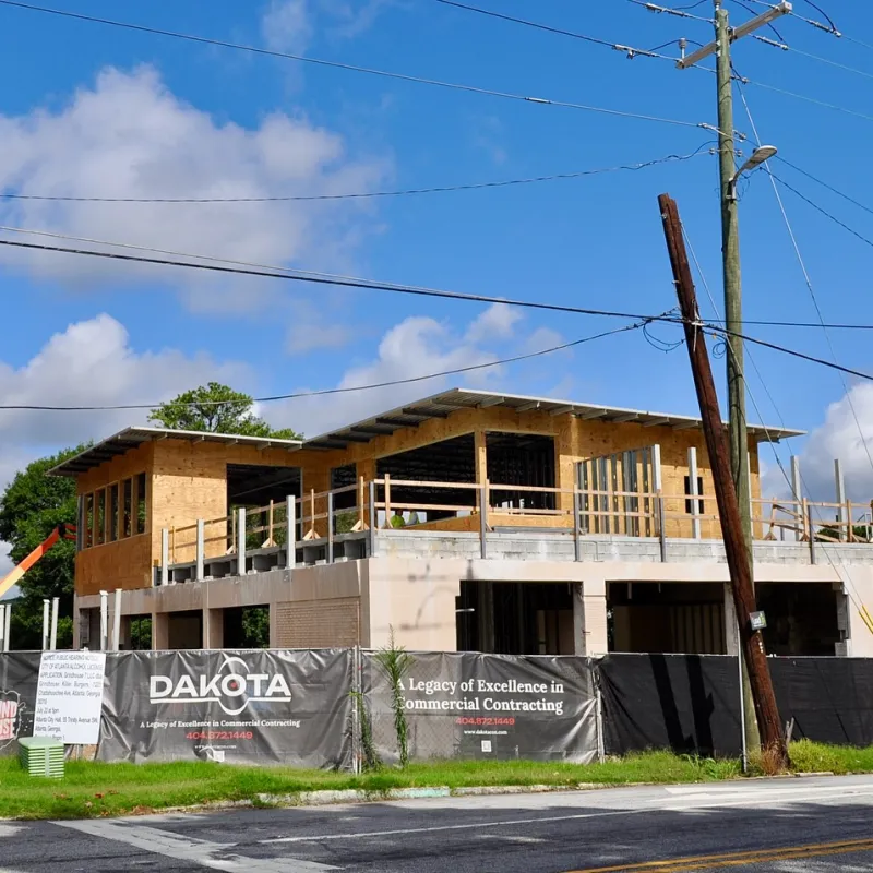 Modern commercial building under construction with Dakota contracting signage and clear blue sky.