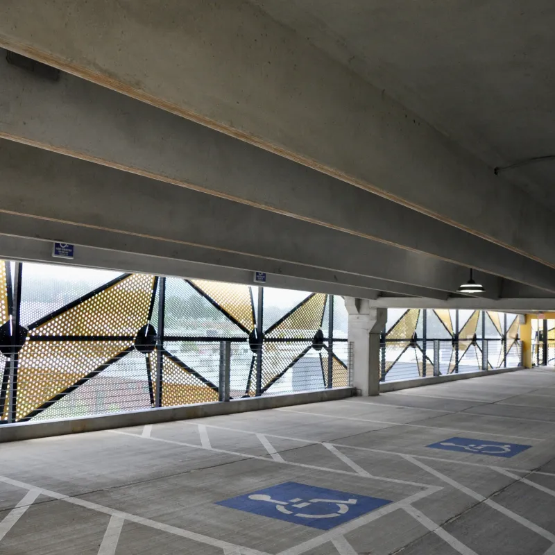 Empty multi-level parking garage with designated handicapped spaces and decorative perforated metal panels.
