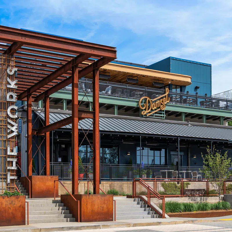Modern building entrance at City Walk with rust-colored metal structure and Dan's restaurant sign under blue sky.