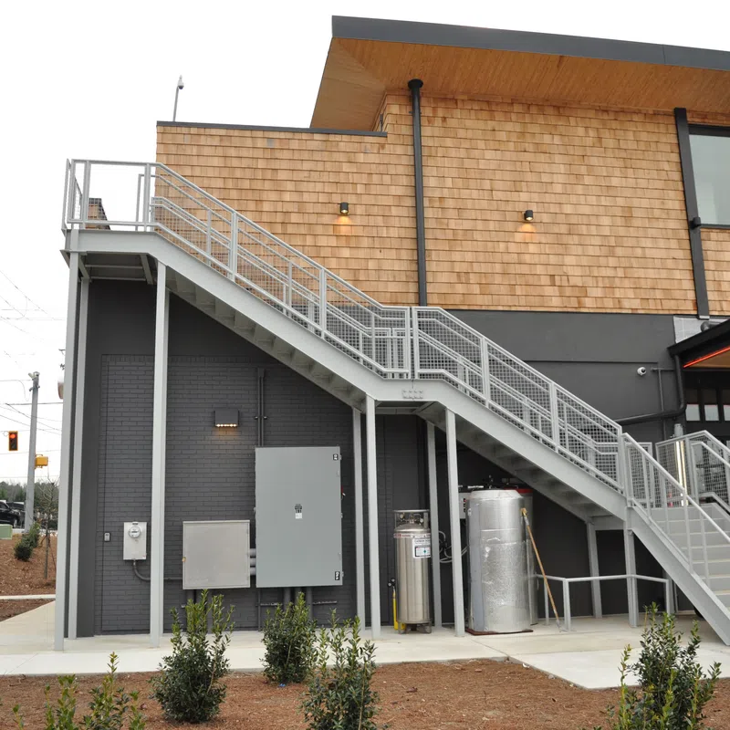 Modern commercial building with exterior metal staircase leading to second floor under natural daylight