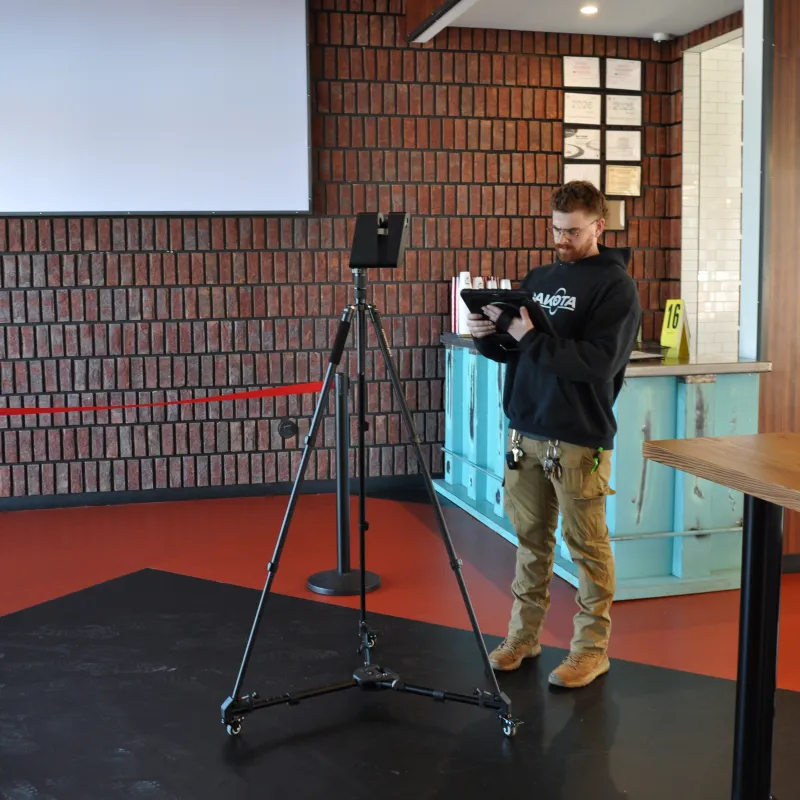 Man adjusting camera on tripod in a modern indoor space with brick wall and wooden counter