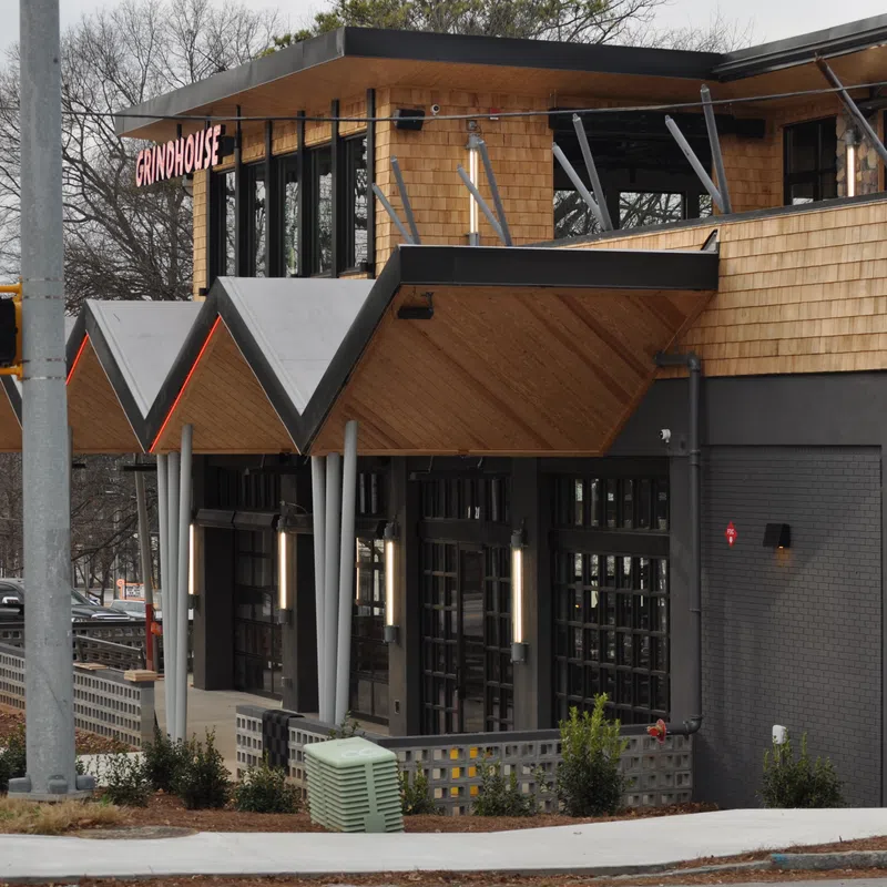 Modern Grindhouse restaurant exterior with wooden accents and geometric roof design on cloudy day