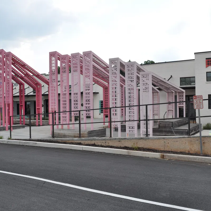 Pink metal architectural installation outside MacDermid Graphics Solutions building on a cloudy day