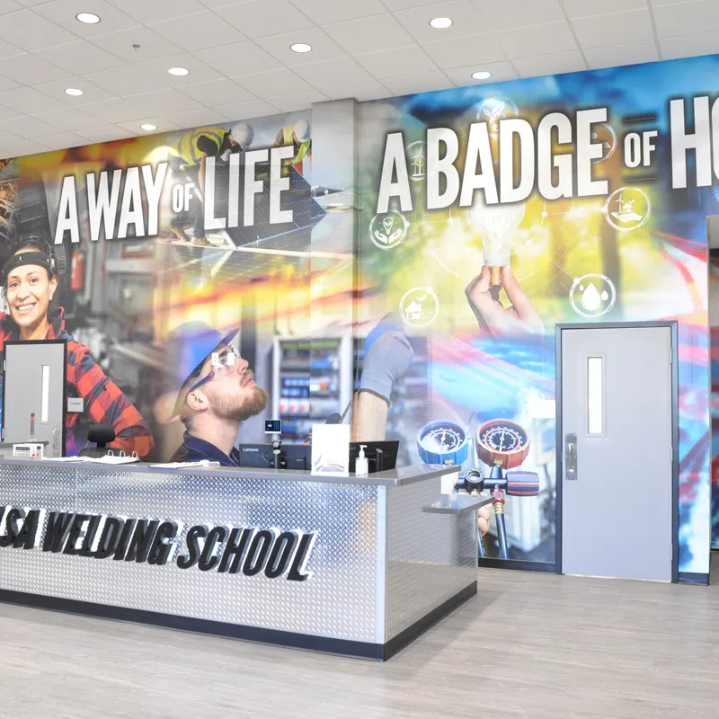 Reception area of Tulsa Welding School with mural reading A Way of Life A Badge of Honor and staff desk