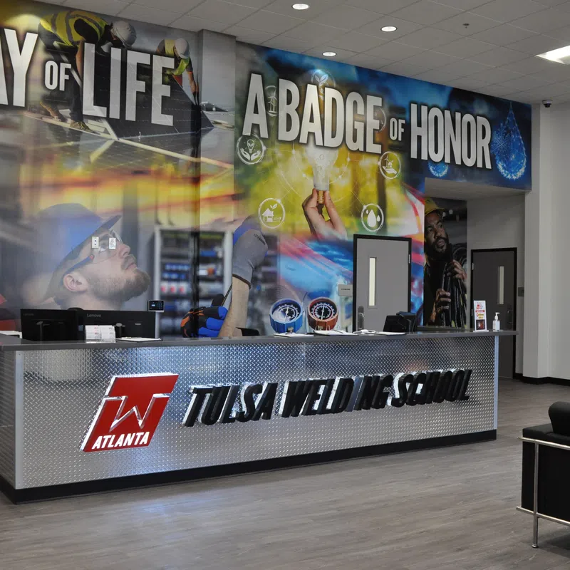 Modern Tulsa Welding School reception with slogan wall art and metal front desk in Atlanta campus lobby