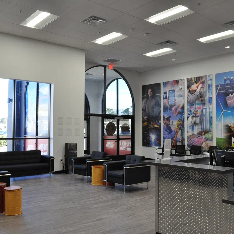 Modern waiting area with black sofas, colorful stools, large windows, and vibrant industrial-themed wall art.
