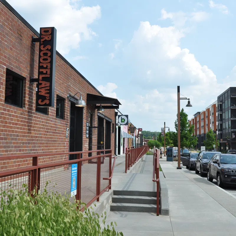 Urban street scene with brick buildings, parked cars, and a sign for Dr. Softlan's on a sunny day.